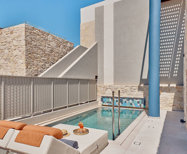 Private outdoor pool with sun loungers, refreshments, and surrounding privacy walls.
