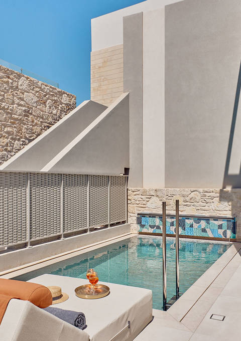 Private outdoor pool with sun loungers, refreshments, and surrounding privacy walls.