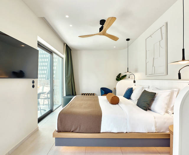 Modern double room with king-size bed, flat-screen TV, and direct access to private pool area.