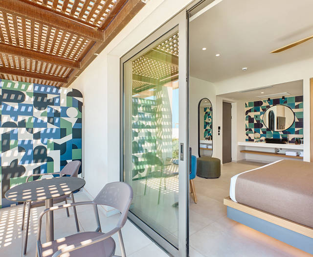 Double room with private shaded balcony, outdoor seating, and interior view of the modern bedroom and bathroom.