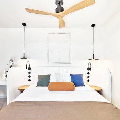 Bright rooftop room with double bed, ceiling fan, and modern minimalist decor.