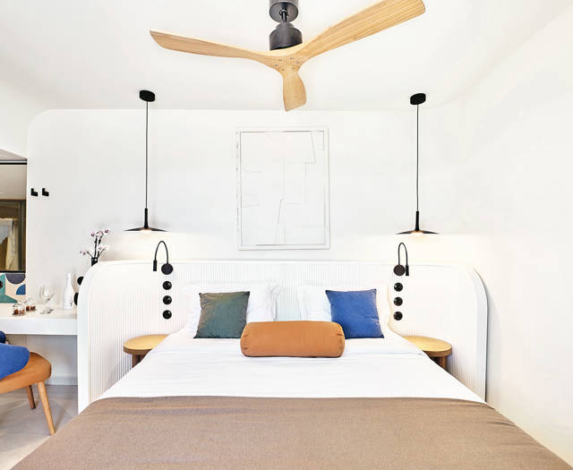 Bright rooftop room with double bed, ceiling fan, and modern minimalist decor.