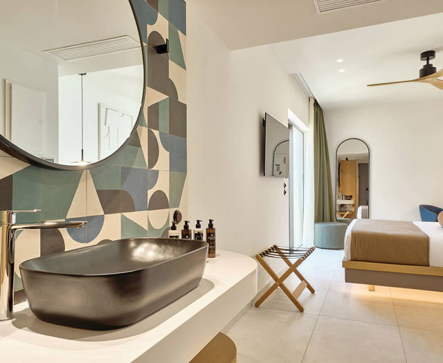 Open-plan room with modern bathroom, large mirror, and view toward the bedroom and garden access.