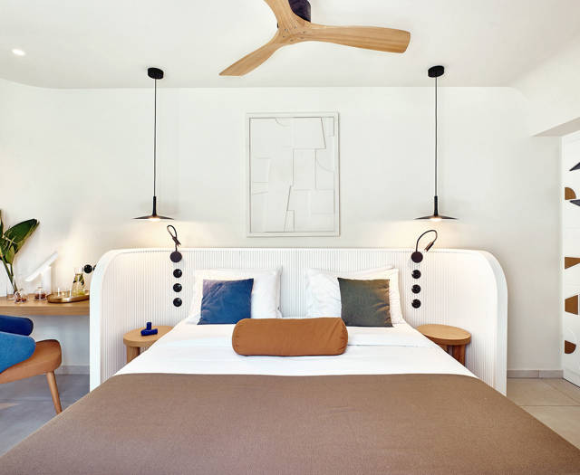 Double bed with pendant lighting, ceiling fan, and a corner desk in a private pool room.