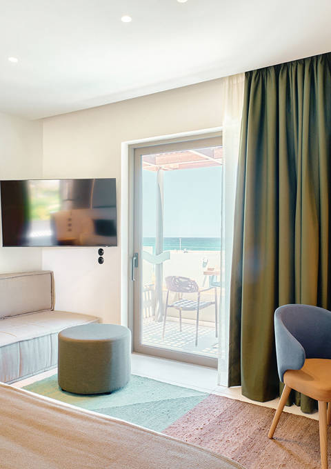 Bright junior suite with double bed, sofa, modern wooden desk and access to a private balcony