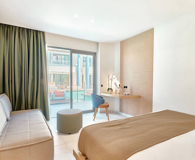 View from the sitting area of a junior suite with direct pool access through large glass doors.