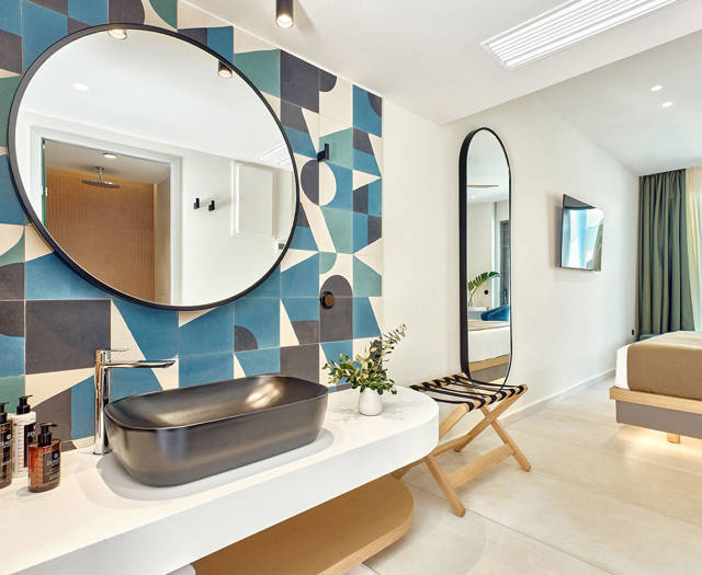 Open-plan bathroom with vessel sink, geometric tile wall, and view into the swim-up room’s bedroom.