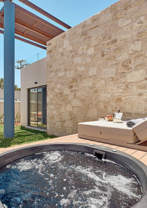 Private garden area with hydromassage tub, sun lounger, and outdoor seating.