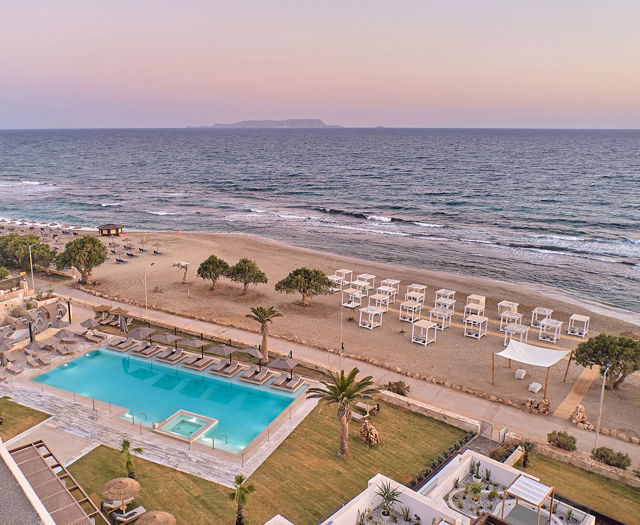 Aerial view of beachfront pool and private loungers on the sand at Kosta Alimia during sunset.