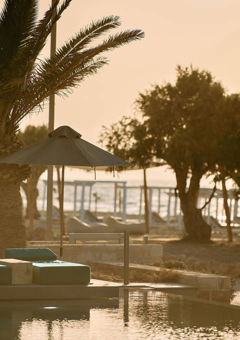Paralos Kosta Alimia pool's green sunbeds and the beach in the background