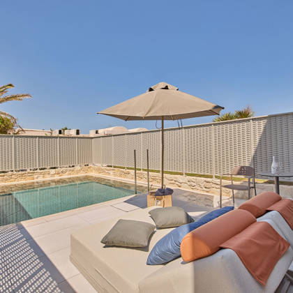 Private outdoor pool with sun loungers, a round table with two chairs, and surrounding privacy walls.