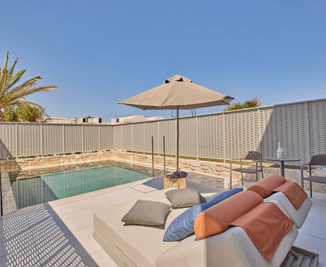 Private outdoor pool with sun loungers, a round table with two chairs, and surrounding privacy walls.