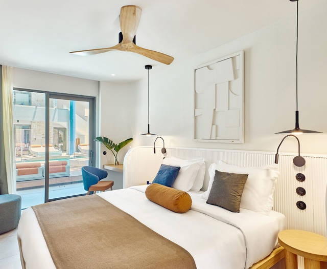 Double room with stylish lighting, warm tones, and sliding doors opening directly to a swim-up pool.