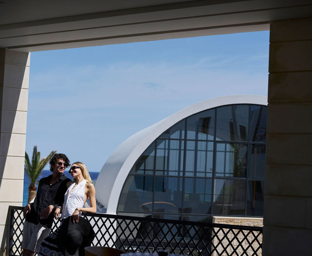 A couple enjoying a moment together at Kosta Alimia, with the resort’s modern architecture and sea view.