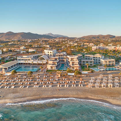 Wide aerial view of Kosta Alimia resort with beachfront loungers, pools, and the surrounding landscape.