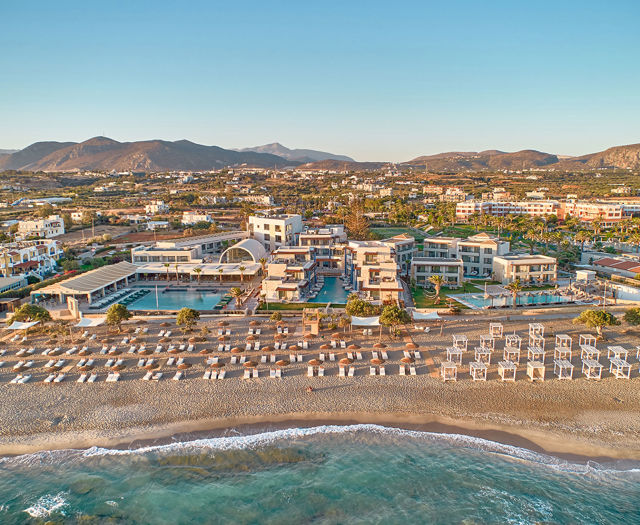 Wide aerial view of Kosta Alimia resort with beachfront loungers, pools, and the surrounding landscape.