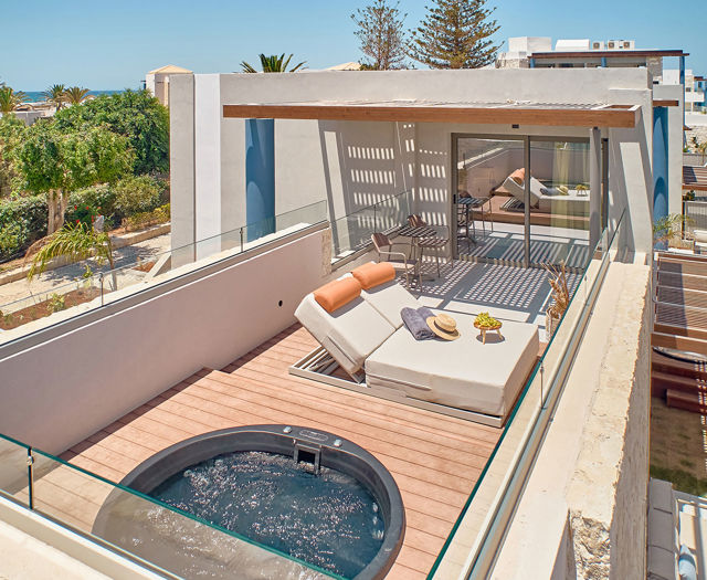 Elevated view of rooftop suite with private hydromassage tub, sun loungers, and covered outdoor seating.