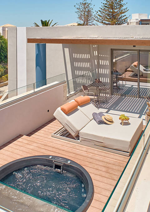 Elevated view of rooftop suite with private hydromassage tub, sun loungers, and covered outdoor seating.