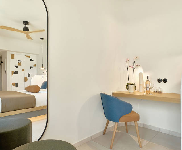 Elegant corner with vanity desk, decorative mirror, and view into the bedroom.