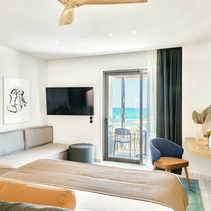Bright junior suite with double bed, sofa, modern wooden desk and access to a private balcony