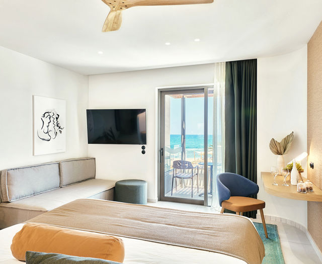 Bright junior suite with double bed, sofa, modern wooden desk and access to a private balcony