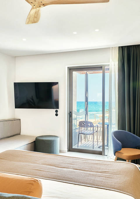 Bright junior suite with double bed, sofa, modern wooden desk and access to a private balcony
