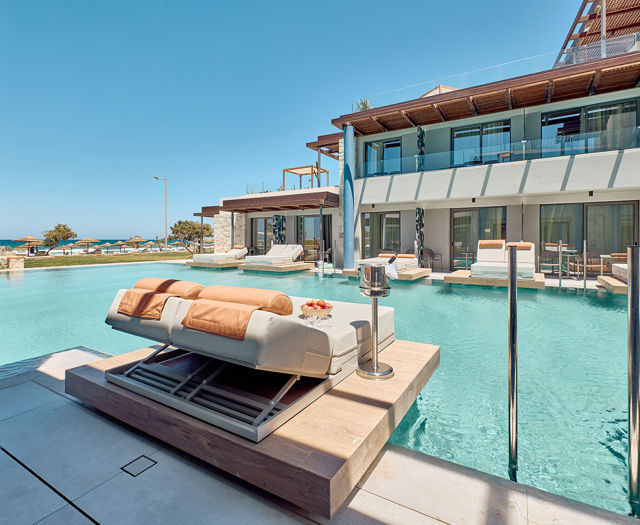 Swim-up room terrace with floating sun loungers, steps into the pool, and side sea view beyond.