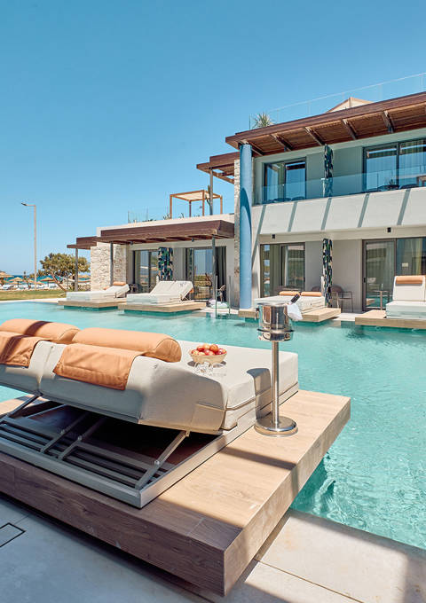 Swim-up room terrace with floating sun loungers, steps into the pool, and side sea view beyond.