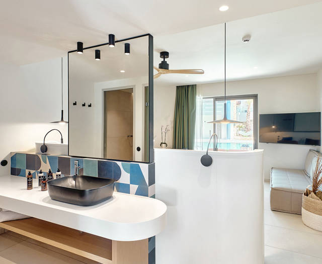 Modern bathroom with black sink, geometric tile backsplash, large mirror, and built-in wooden shelves and room view