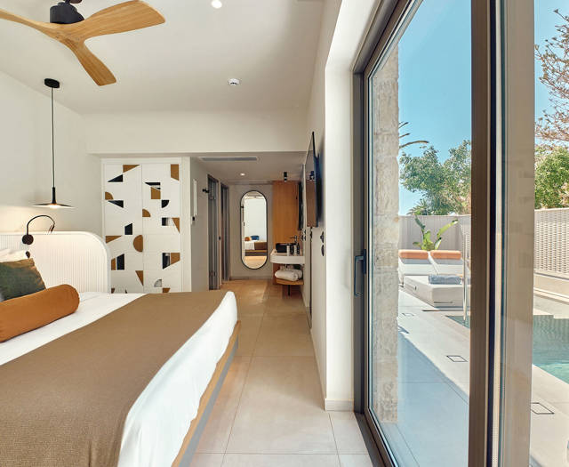 Bedroom with direct pool access, large glass doors, and view into the modern bathroom area.