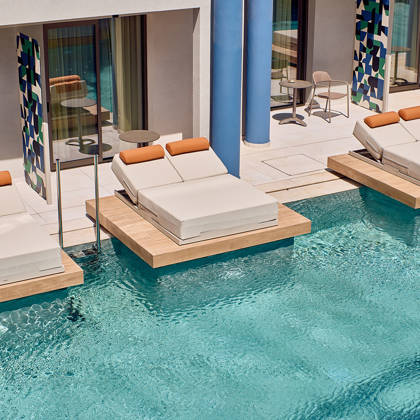 Floating double sunbeds over private pool area outside modern rooms