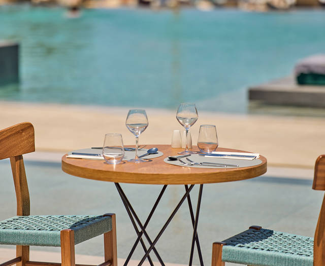 Intimate round table set for two beside a serene pool 