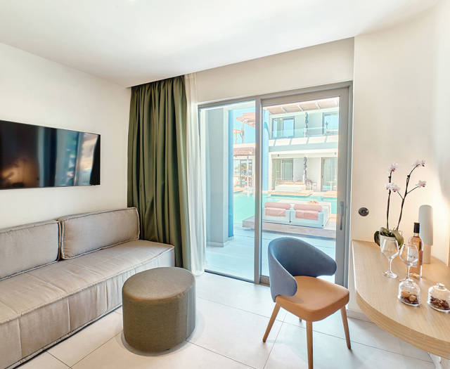 View from the sitting area of a junior suite with direct pool access through large glass doors.