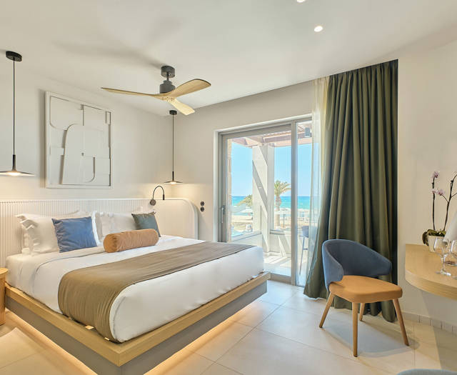 Modern double room with sea view, featuring a large bed, balcony, and contemporary decor.