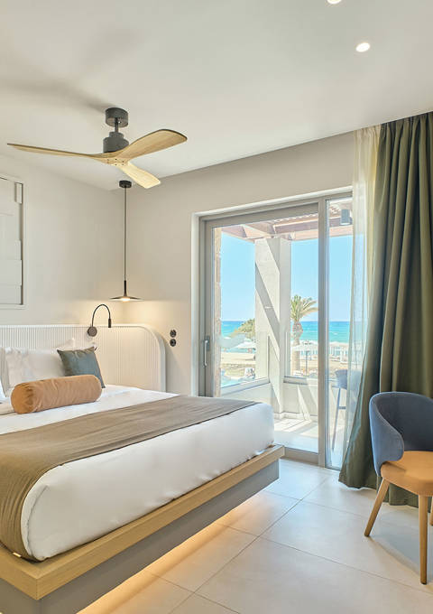 Modern double room with sea view, featuring a large bed, balcony, and contemporary decor.