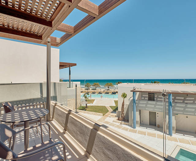 Junior suite's private balcony with two chairs and a table having a side sea view