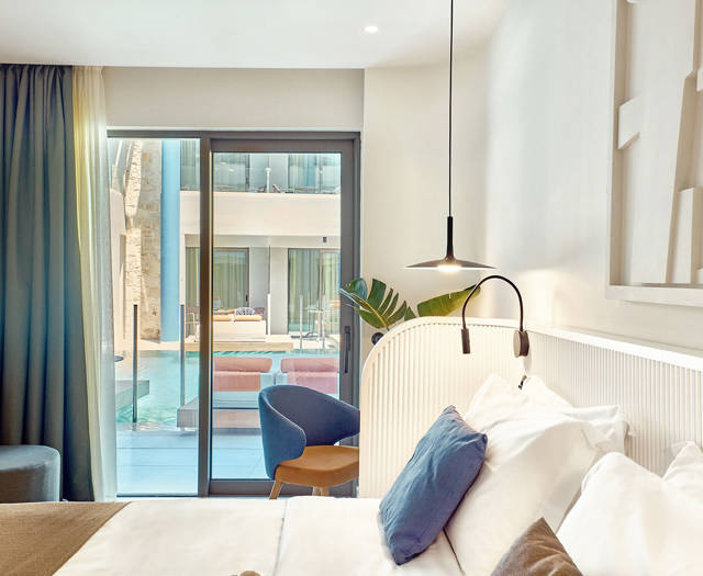View from the bed of a swim-up room with direct pool access through large glass doors.