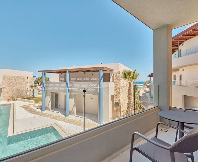 Private balcony with pool and side sea view, furnished with a small table and two chairs.