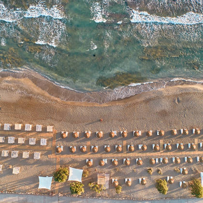 Aerial view of the beach with sunbeds and umbrellas by the sea.