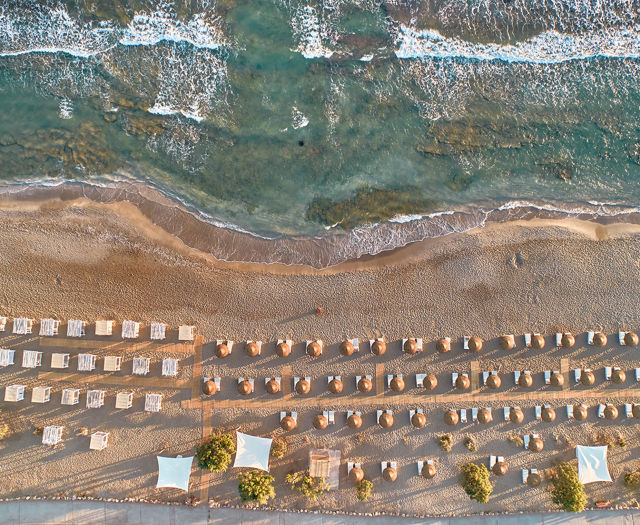 Aerial view of the beach with sunbeds and umbrellas by the sea.