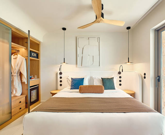 Side sea view room with modern double bed, open wardrobe, and direct access to a private balcony.