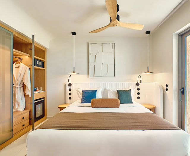 Side sea view room with modern double bed, open wardrobe, and direct access to a private balcony.