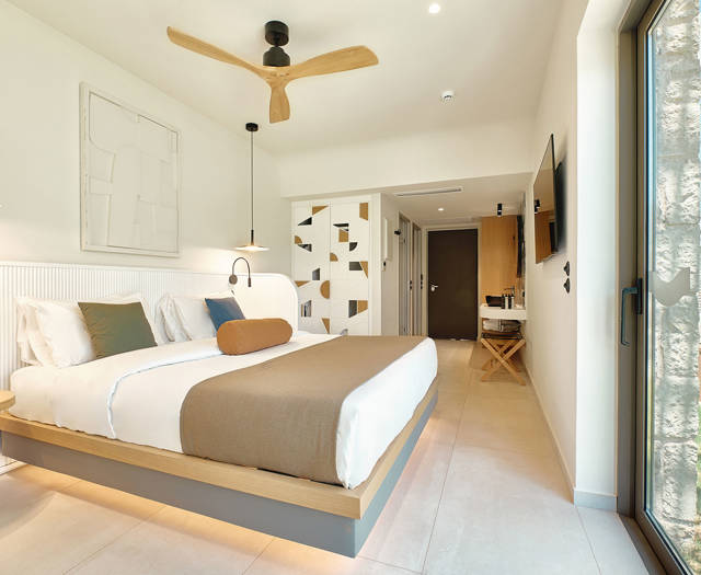 Sunlit bedroom with modern design, garden access, and view toward the entrance and bathroom area.