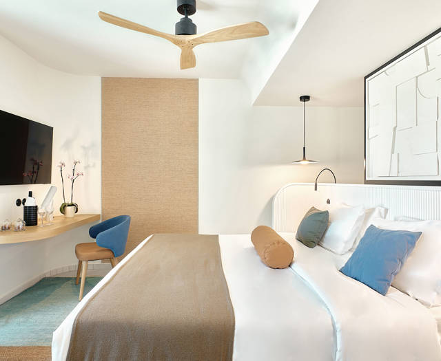 Side sea view room with cozy double bed, wall-mounted TV, and a stylish work desk