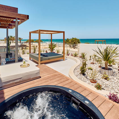 Private terrace with a hot tub, sunbeds, canopy daybed, and sea view framed by minimalist landscaping.