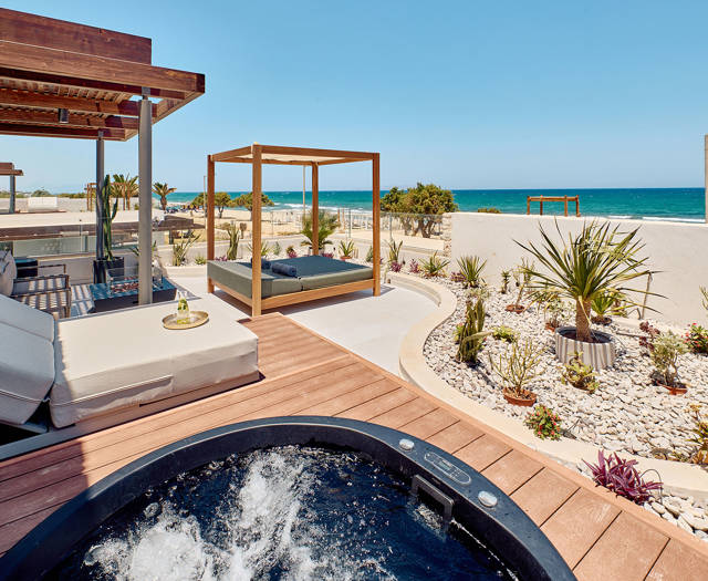 Private terrace with a hot tub, sunbeds, canopy daybed, and sea view framed by minimalist landscaping.