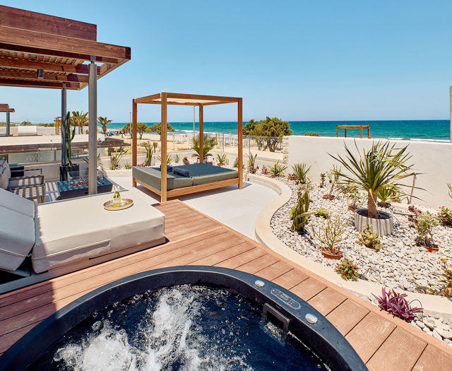 Private terrace with a hot tub, sunbeds, canopy daybed, and sea view framed by minimalist landscaping.