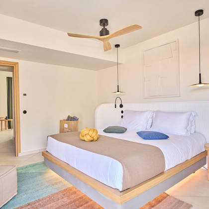 Double bed with pendant lighting, ceiling fan, and a corner desk in a private pool suite.
