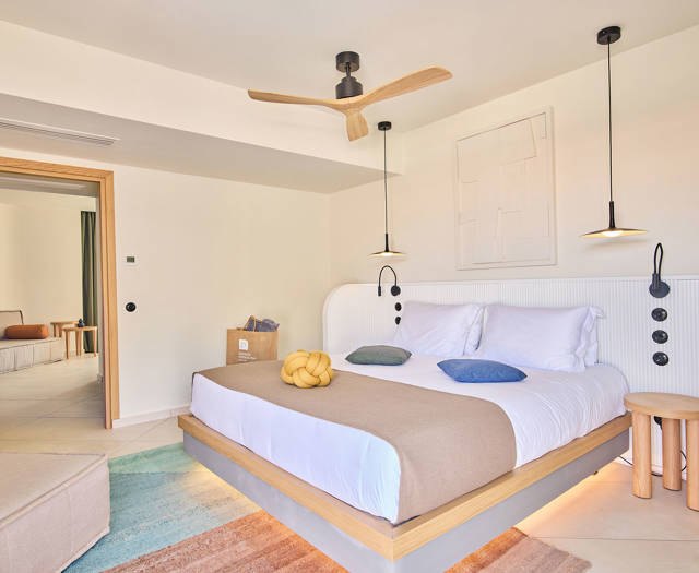 Double bed with pendant lighting, ceiling fan, and a corner desk in a private pool suite.