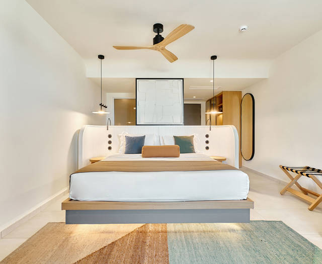 Bright and cozy junior suite with double bed, and colorful area rug.